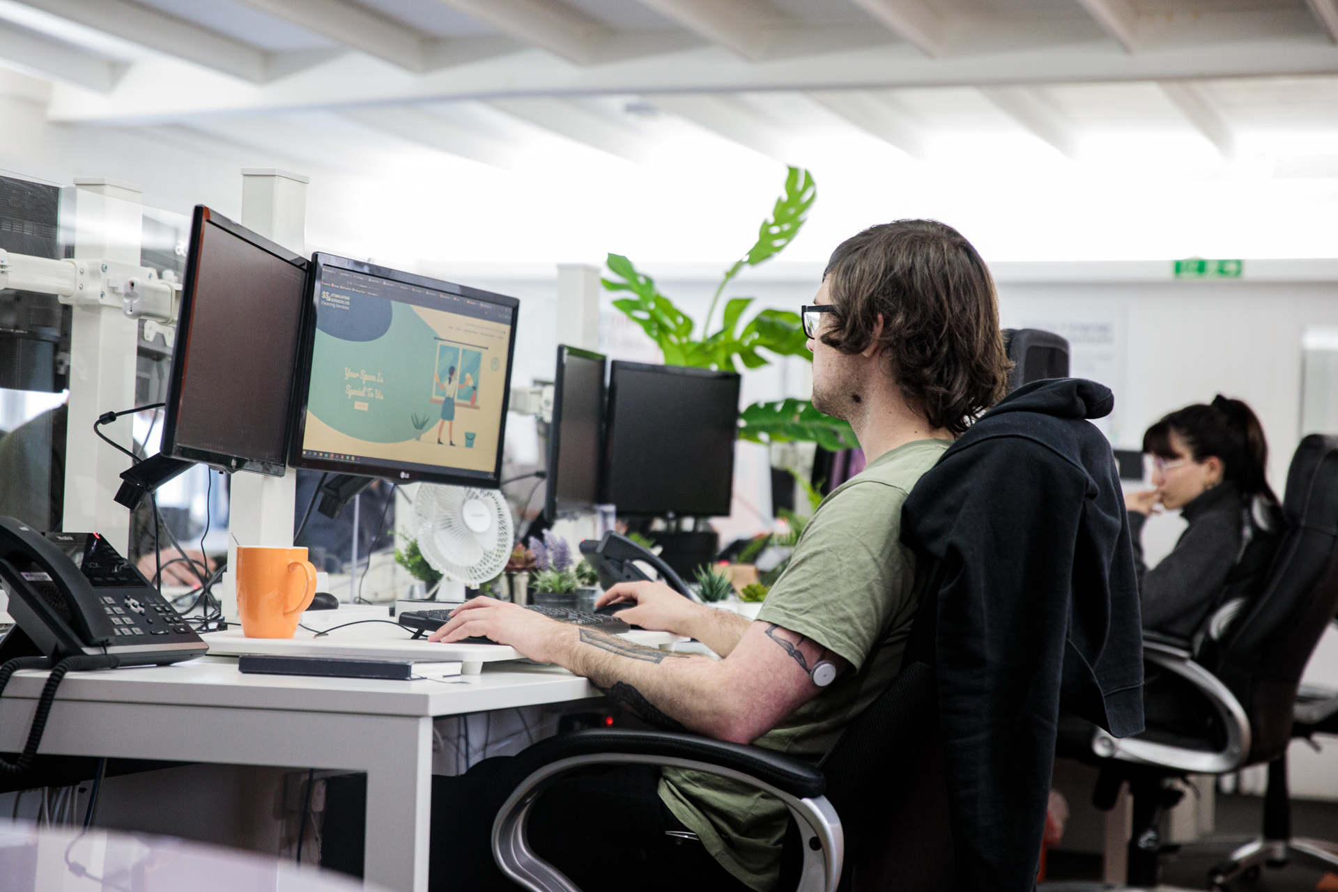 A male website designer, sat in an office chair on his computer